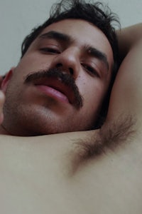 a man with a mustache laying on a bed