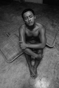 black and white photo of a man sitting on a rug